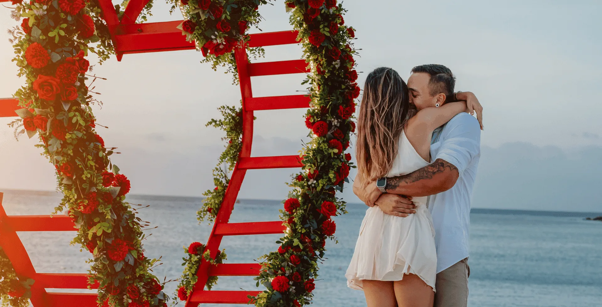 Couple embracing beneath a floral beach installation